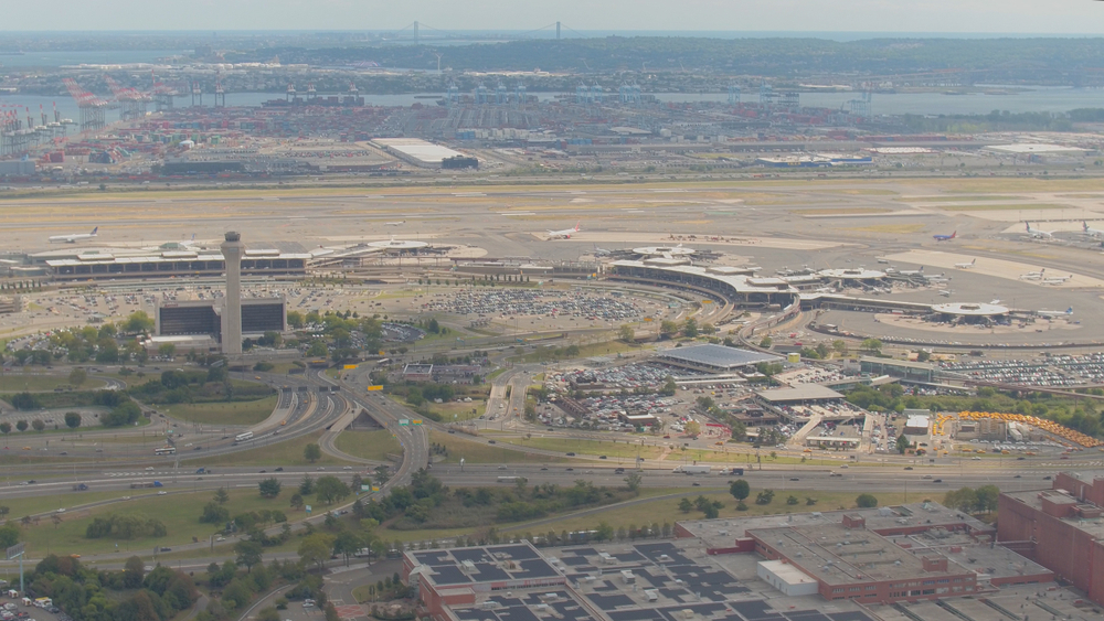 Señal de carretera hacia Newark Liberty International Airport delante de la torre de control del aeropuerto
