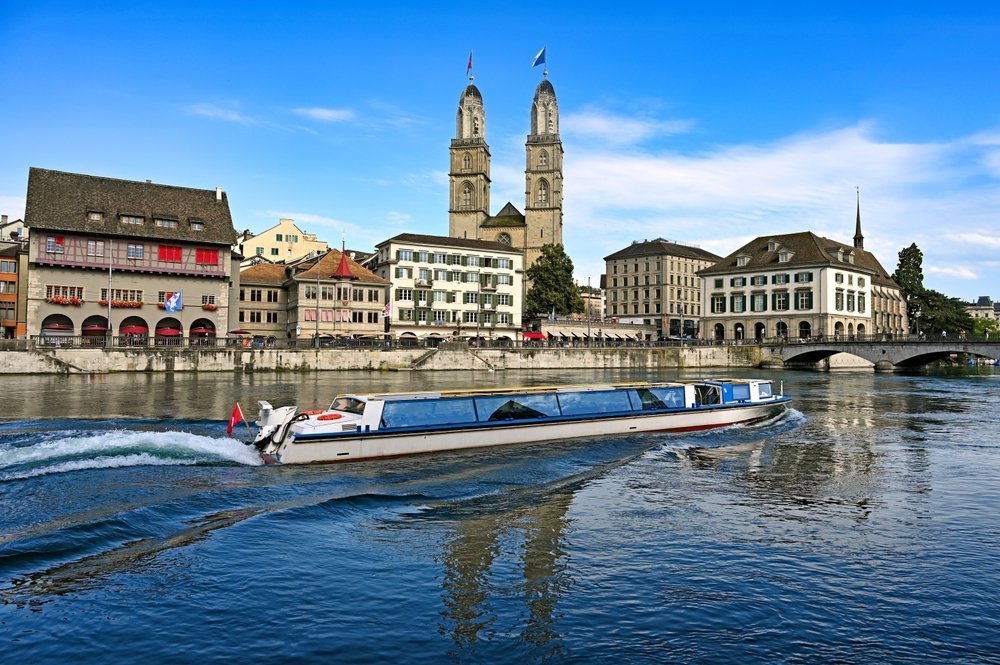 Qué ver en Zúrich: 18 cosas que hacer, del casco antiguo y los vitrales de Chagall al Uetliberg 24 Barco turístico navegando por el Limmat en Zúrich con el Grossmünster al fondo