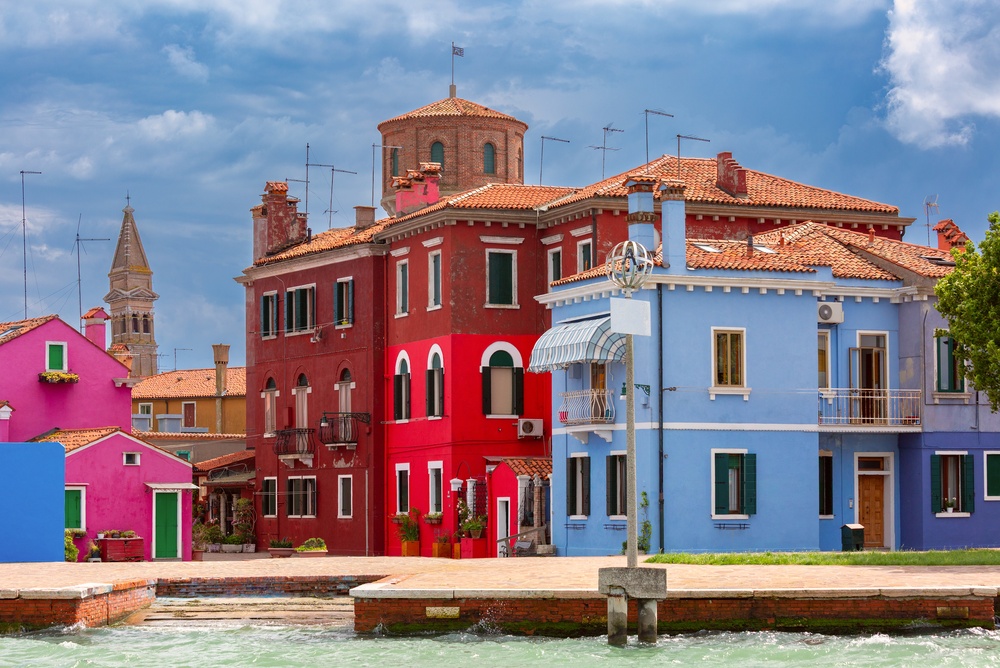 Casas de colores junto a un canal en Burano con el campanario de la iglesia al fondo