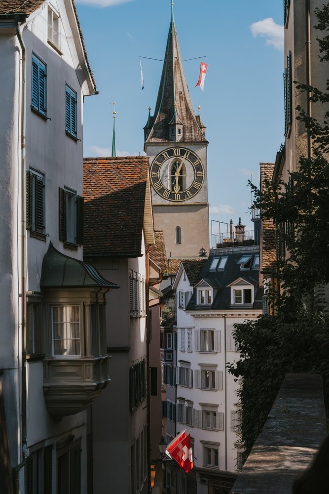 Qué ver en Zúrich: 18 cosas que hacer, del casco antiguo y los vitrales de Chagall al Uetliberg 20 Calle del Niederdorf en Zúrich con banderas suizas y la torre de St. Peter al fondo