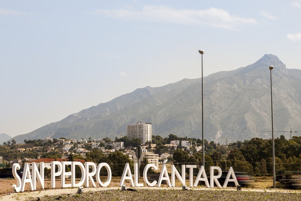 Cartel de bienvenida a la entrada de San Pedro de Alcántara con la montaña La Concha al fondo