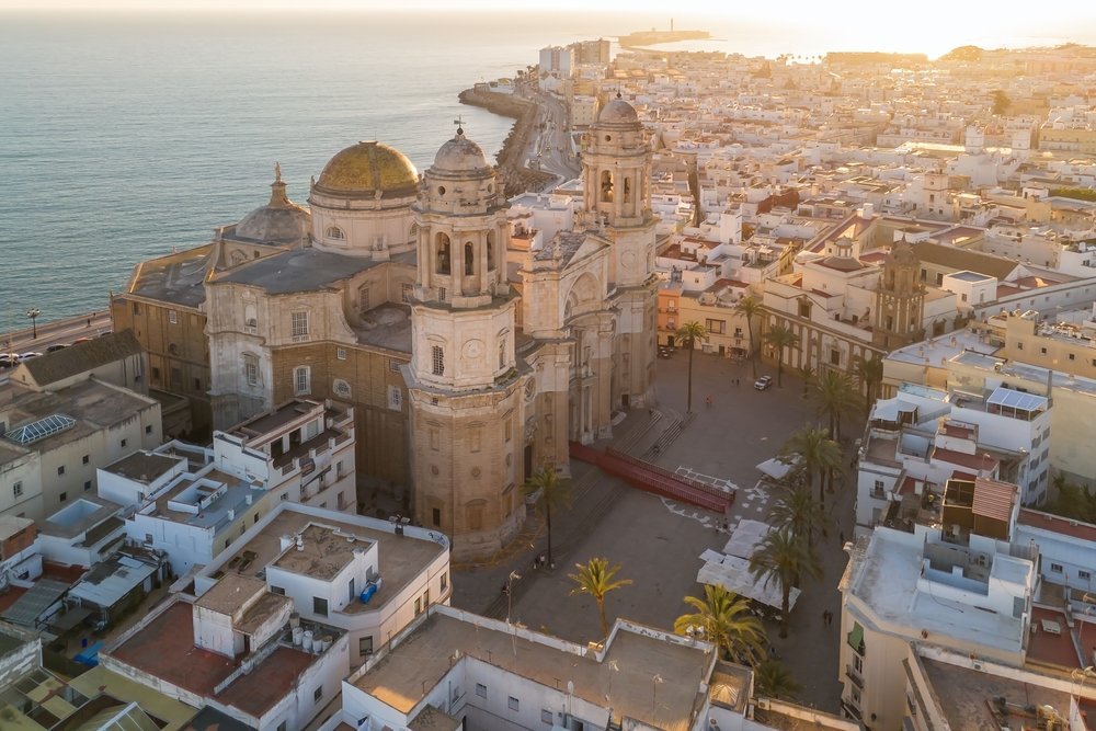 Vista aérea de la catedral y del casco antiguo de Cádiz al atardecer, con el océano Atlántico al fondo