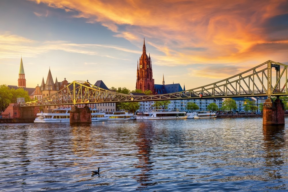 Skyline de Fráncfort con la pasarela peatonal Eiserner Steg y la Catedral Imperial sobre el río Meno al atardecer